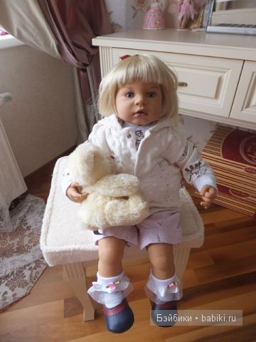 Кукла сидит на пуфике