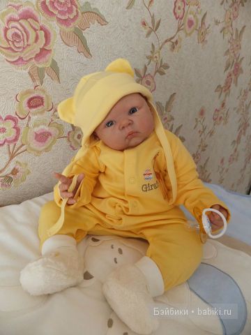 На комоде, в жёлтом, сидит, шапка набок