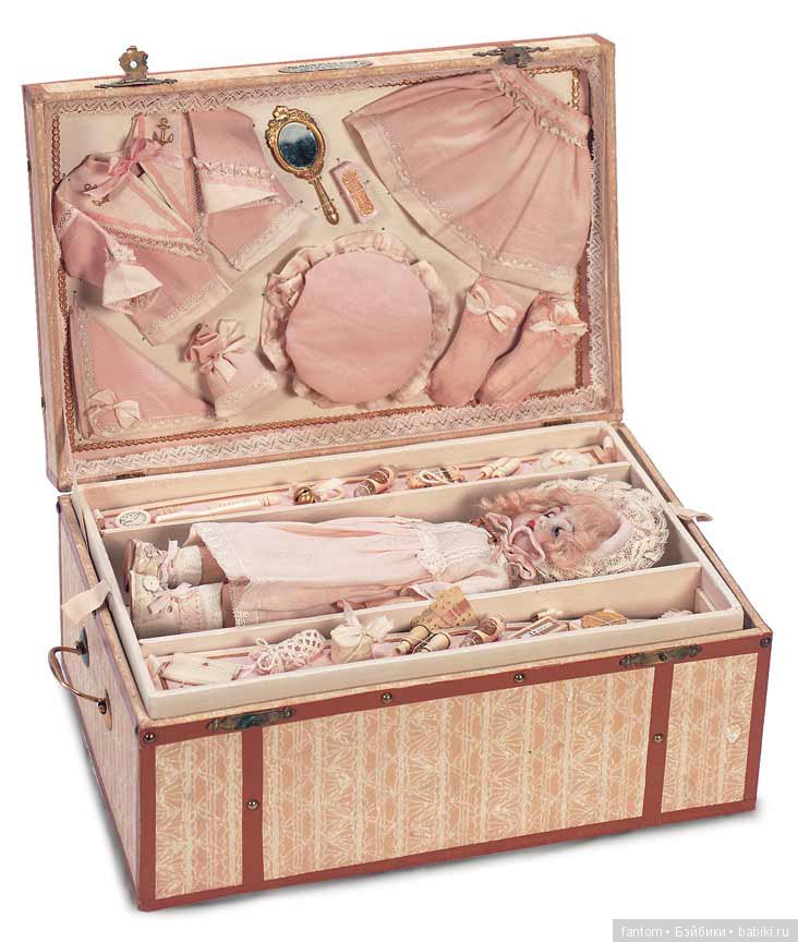 Эксклюзивная роскошная презентация для престижного парижского магазина кукол, около 1900 года. Исключительнейший ансамбль включает розовую куртку и юбку из хлопка с bonnet, носки и платок, включая корсет bebe,каждое изделие с розовыми шелковыми тесемками, розовая накидка из фланели и одеяло,и 18 малюсеньких вспомогательных аксессуаров, такие как щетки,мыла,бутылки одеколона, погремушка, очки для  оперы и др.