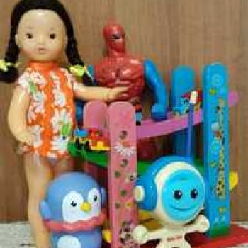 Юля изучает игрушки с благотворительной полочки.